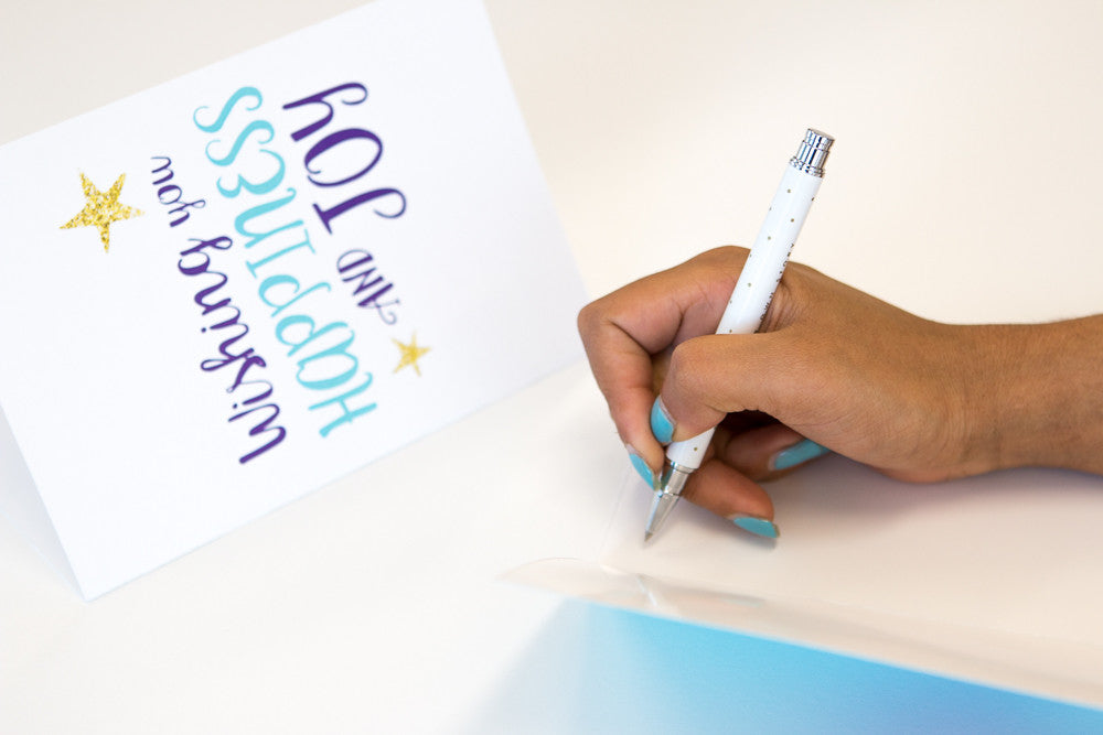 Hand holding pen and writing in printed Starlight Christmas Card 